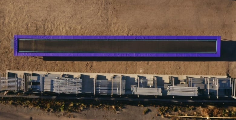 A birds eye view of a long trampoline in a field outside. 