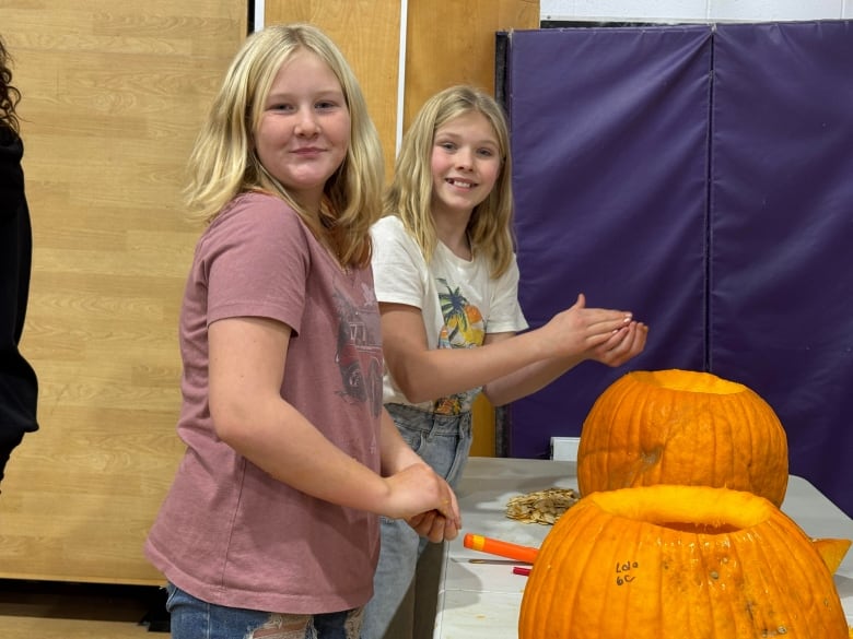 Two girls with blonde hair smile at the camera