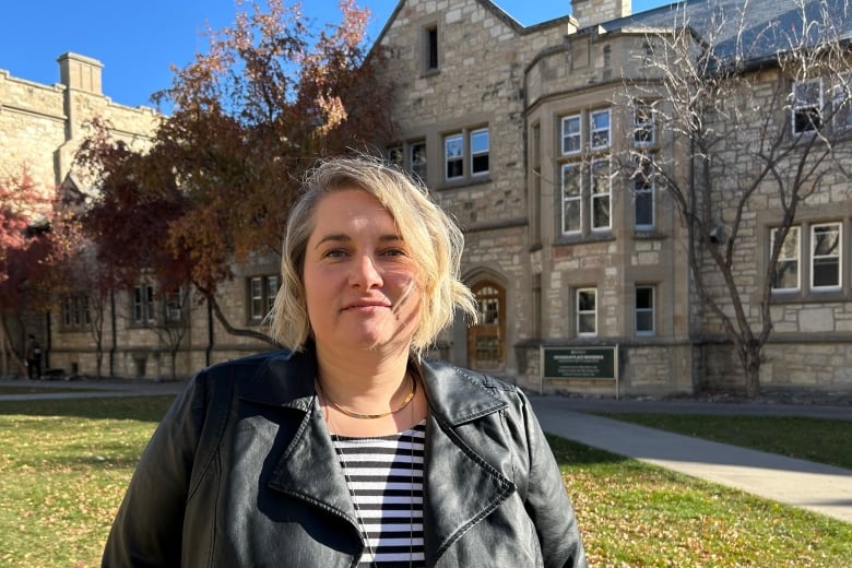 A woman stands in front of a building.