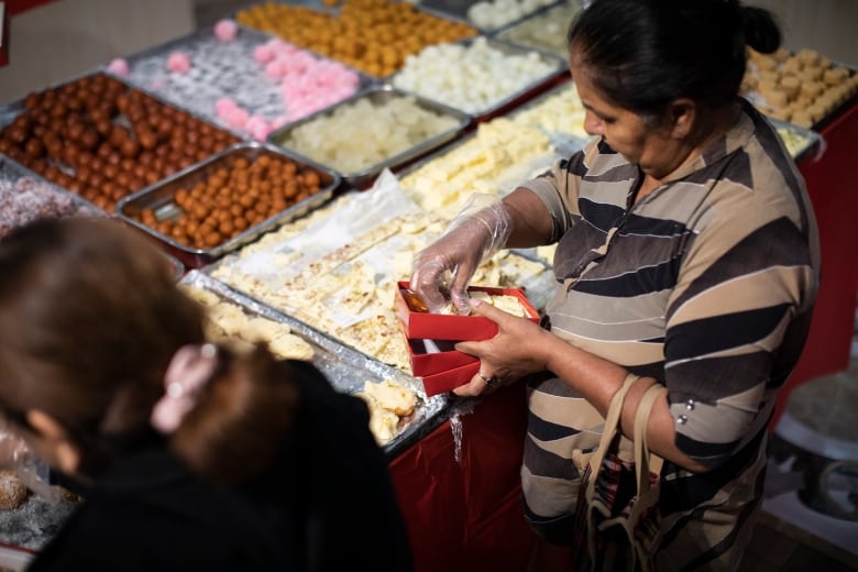 A woman puts sweetmeats into a box at a store.