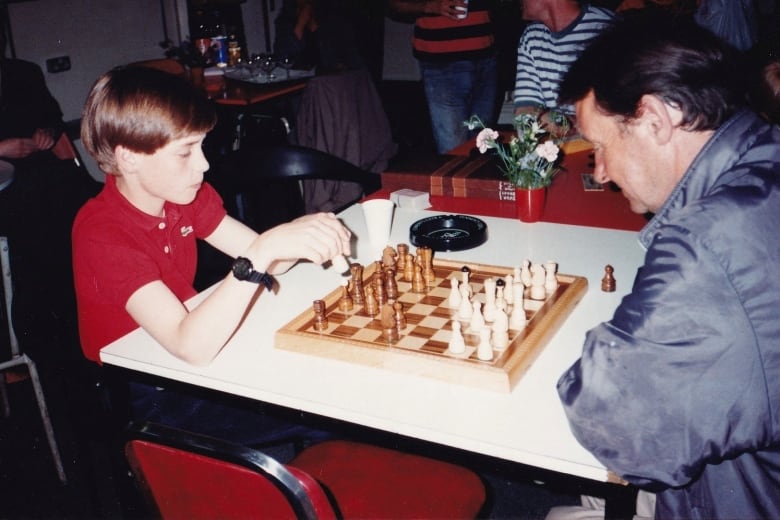 A child plays chess with an adult.