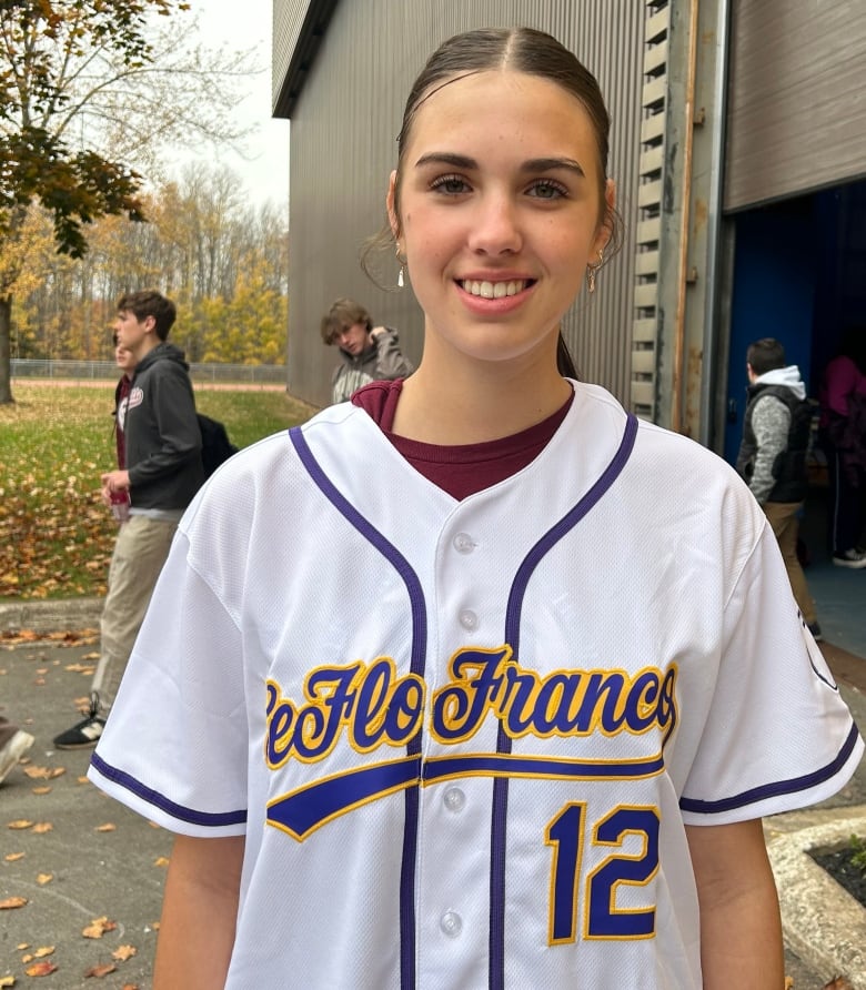 A white girl with brown hair, wearing a white jersey.