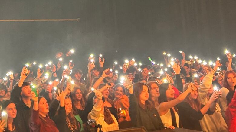 High school students waving their phones with flashlights on.