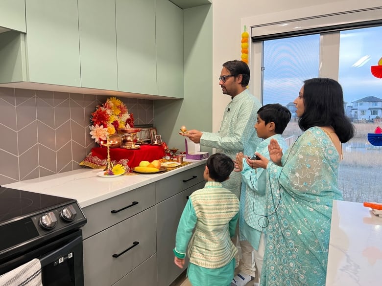 A group of people looking at a small altar on a kitchen counter