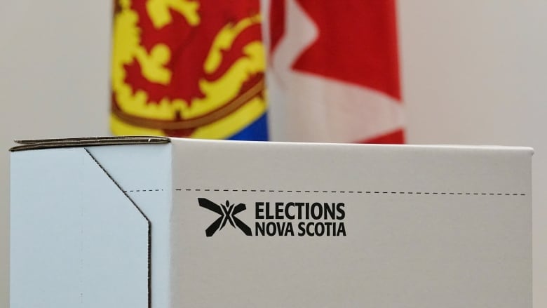 A ballot box is shown in front of a Nova Scotia and Canadian flag.