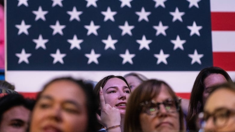 Woman stand in the foreground of an  american flag