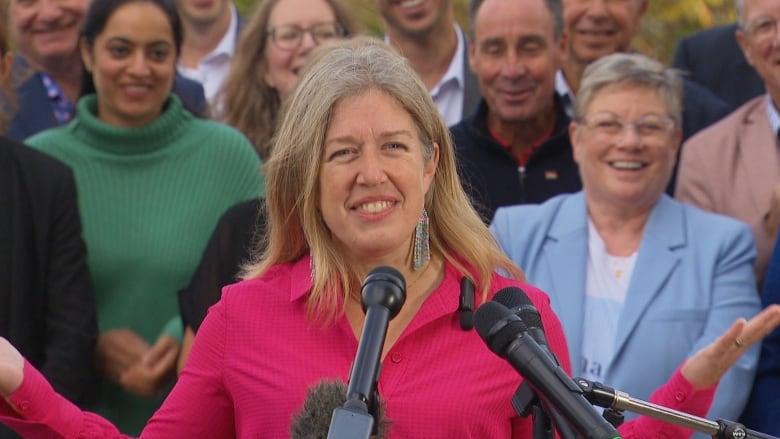 A smiling woman with a group of people behind her.