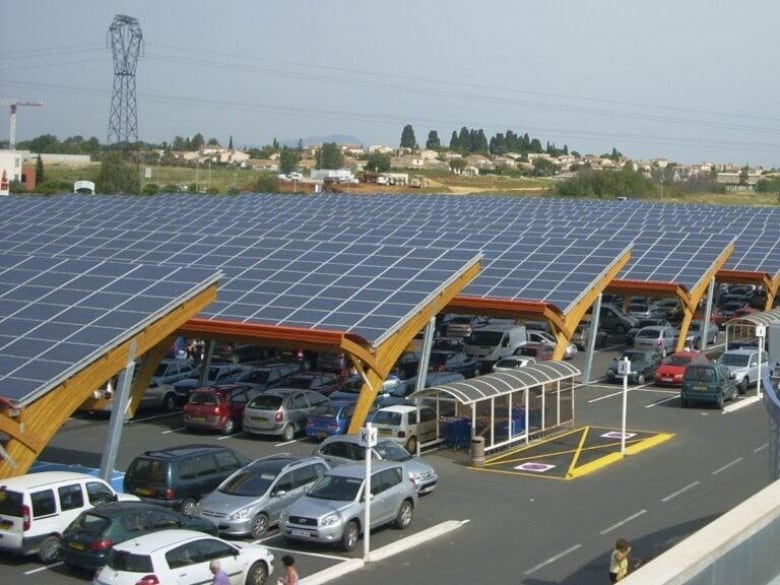 Parked cars covered with solar panel structures.