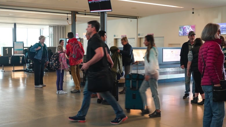 A group of people walk past in an airport.