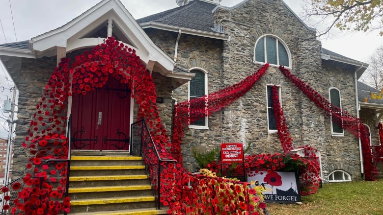 An old brick church is decorated with about 5,000 bright red, hand-made poppies. 