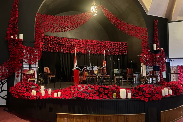 Approximately 5,000 bright red poppies are on display on a stage inside an old church. 