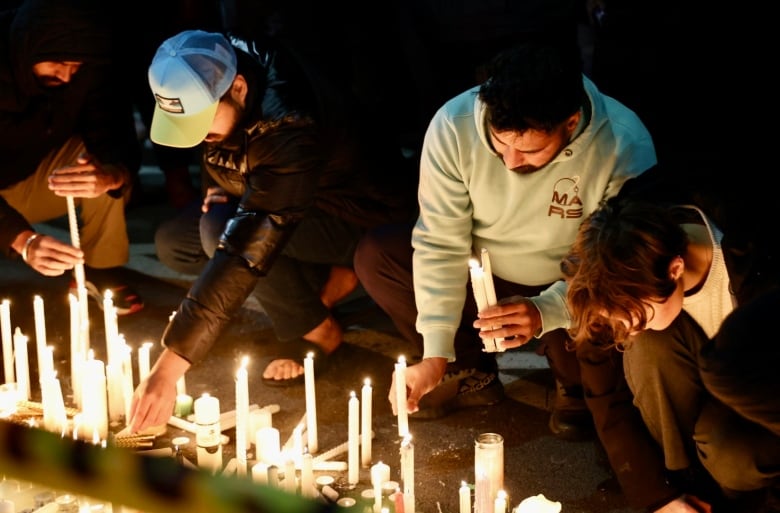 A man is shown kneeling down lighting candles.