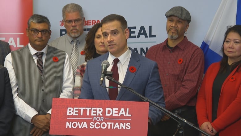 Man standing at podium with a row of people behind him. 