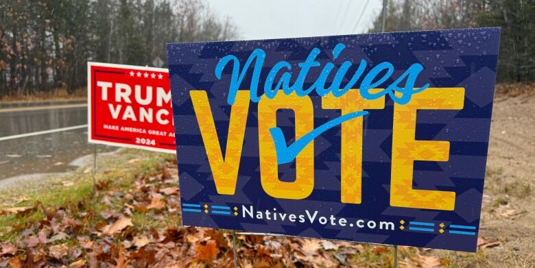 A sign reads Natives Vote in the foreground, with a Trump-Vance sign in the background 