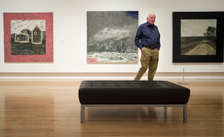 A man is pictured in front of a series of paintings.