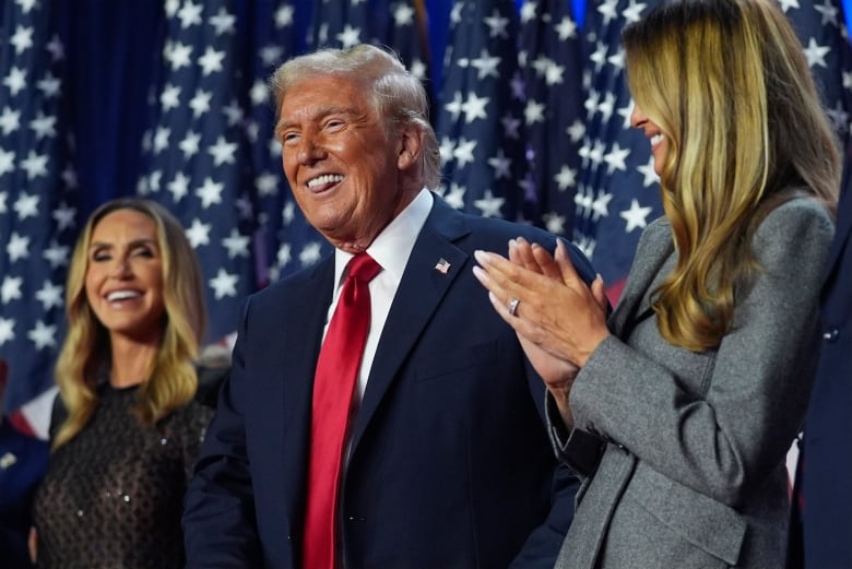 Republican presidential nominee former President Donald Trump stands on stage with former first lady Melania Trump, as Lara Trump watches, at an election night watch party at the Palm Beach Convention Center, Wednesday, Nov. 6, 2024, in West Palm Beach, Fla.