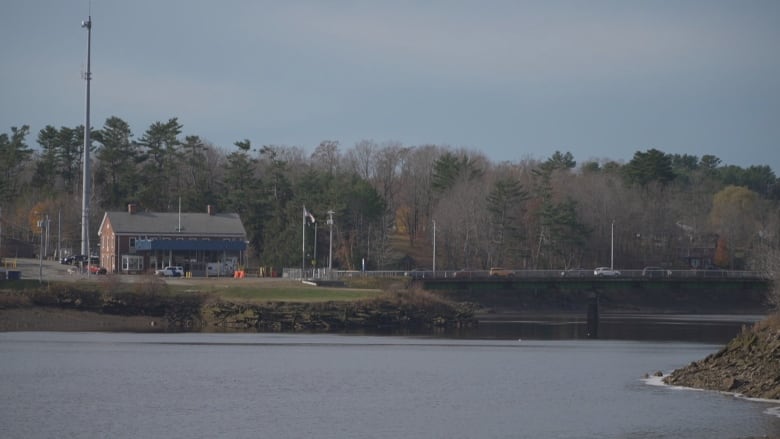 A building sits on a piece of land above a river.