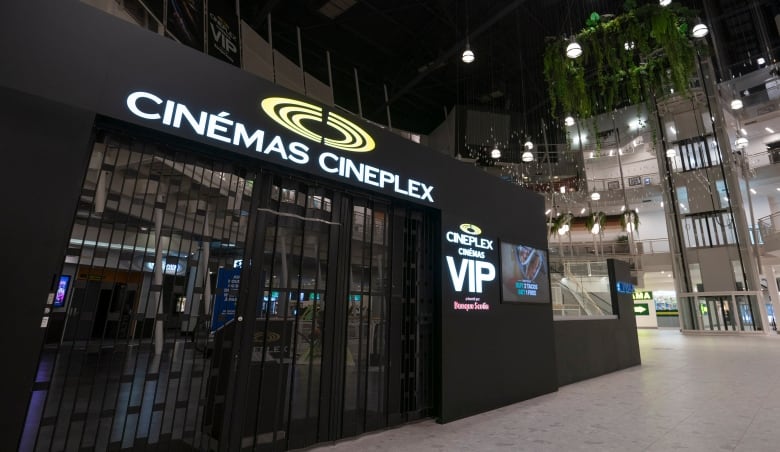 A black building with the words Cinemas Complex on it is shown at a sort of tilted angle from below. The building looks closed, with black gates pulled across the entrance. 