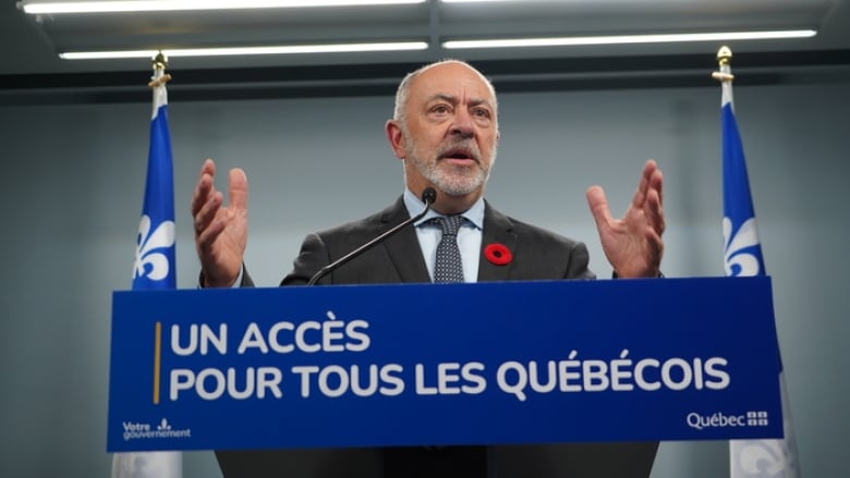 The health minister is pictured speaking behind a podium