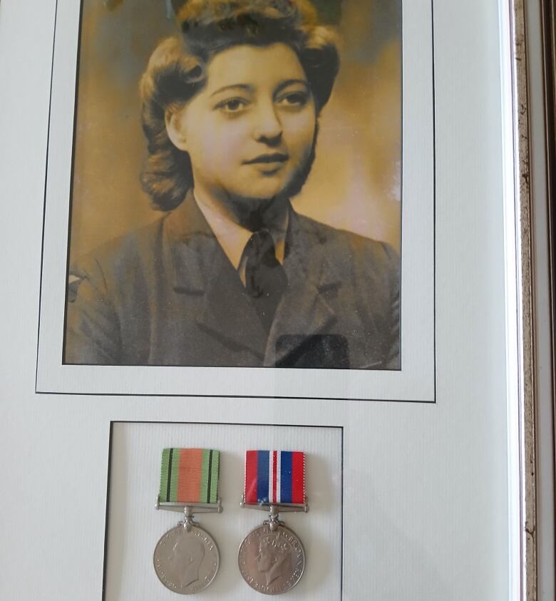 An antique photo of a woman in a military uniform, with two medals below