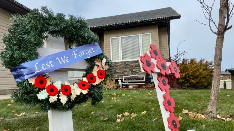 A front lawn that has white crosses one with a wreath that reads 