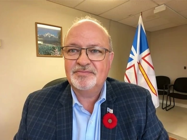 A smiling man wearing a suit sits in a waiting area.