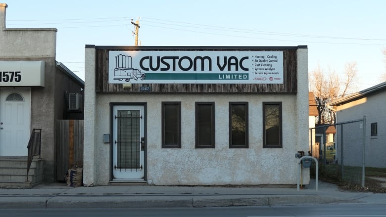 The exterior shot of a business with a white wall and windows. 