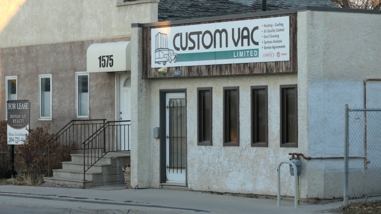 The exterior shot of a business with a white wall and windows.