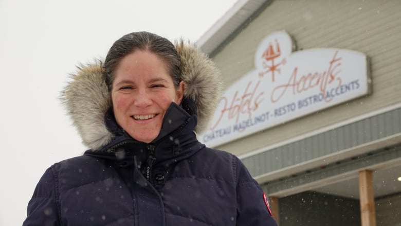 A woman wearing a coat smiling in the snow. 