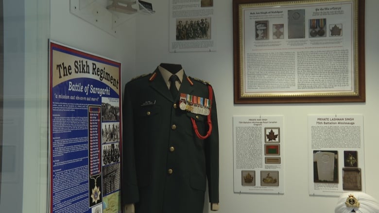 A military uniform on a manikin and multiple plaques detailing military history.