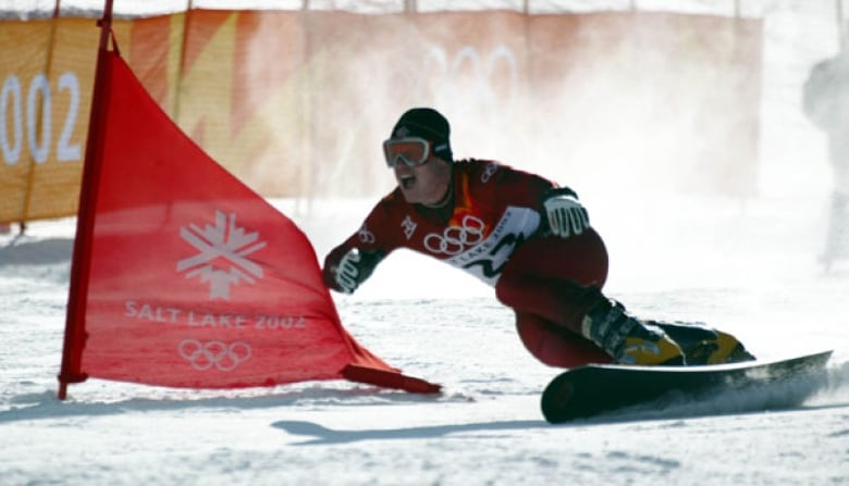 A snowboarder in red races down a snow-covered hill