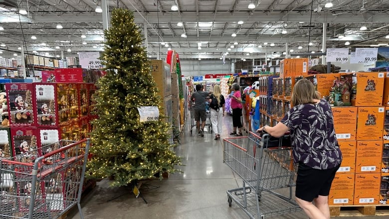 A shopper passes by a Christmas tree and other christmas displays in a store