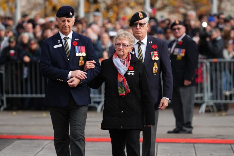 Silver Cross Mother Maureen Anderson is escorted by Steven Clark (left), national executive director of the Royal Canadian Legion, as she arrives at a Remembrance Day ceremony at the National War Memorial in Ottawa on Monday, Nov. 11, 2024.