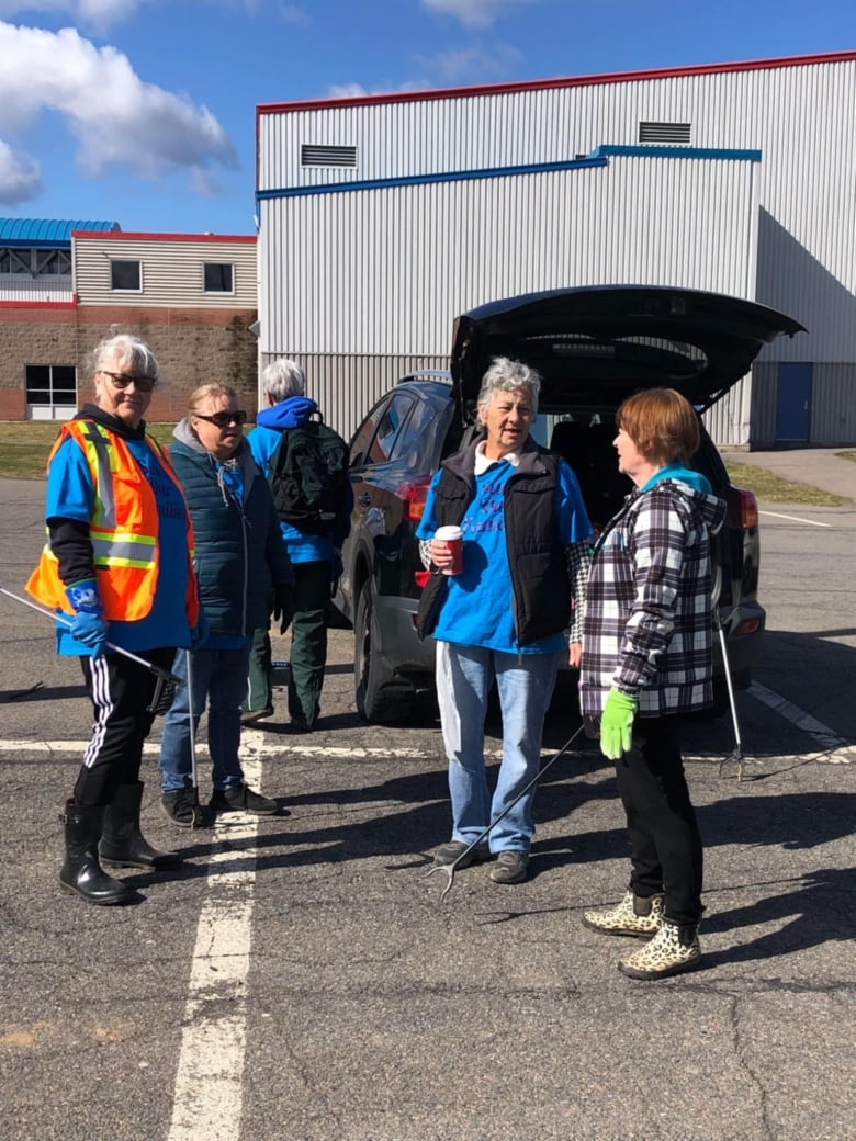 a group of people stand near the trunk of an SUV. 