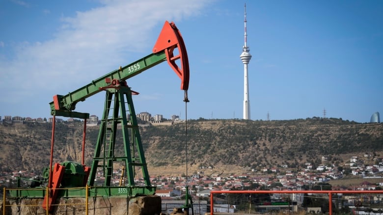 Pumpjack with city and big tower in background