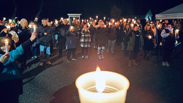 People standing in a circle holding candles.