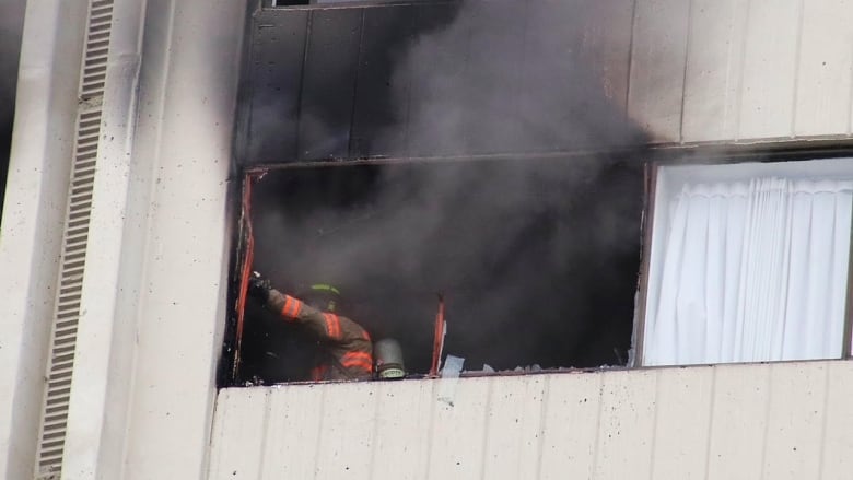 A firefighter is pictured in a window that is clearly on fire.