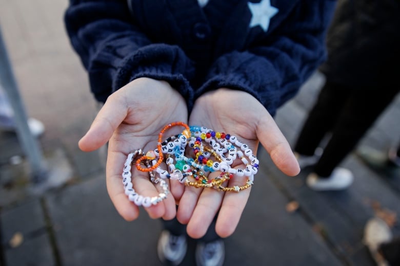 A closeup of a person cupping both hands that's holding friendship bracelets, outside Rogers Centre.