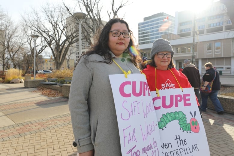 Pam Ryder is standing next to Alyssa Bryant outside in downtown Saskatoon with buildings behind them