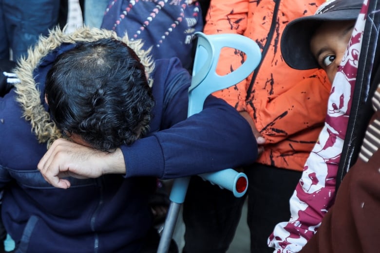 A boy looks on as a mourner reacts.