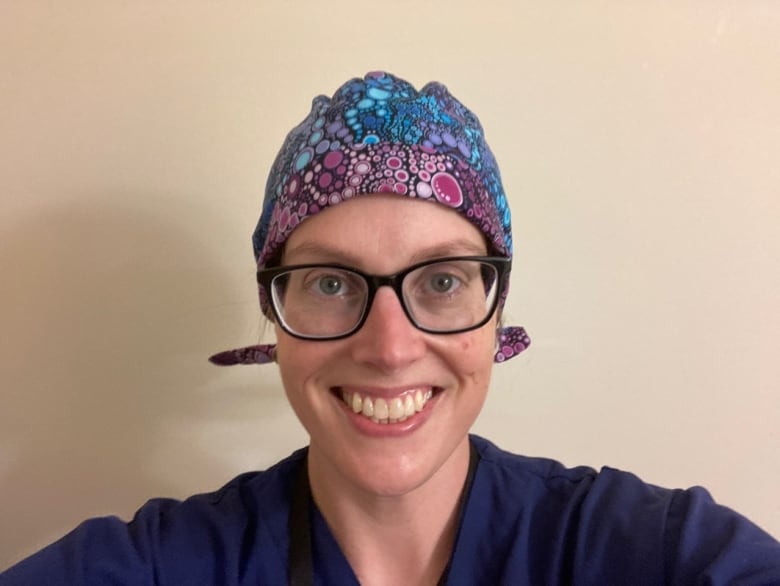 A woman in a scrub cap is smiling at the camera. She is seen from the neck up.