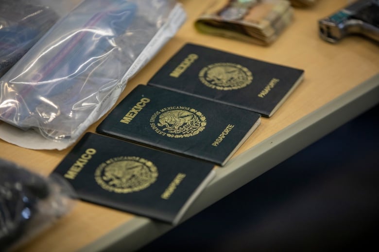 Three Mexican passports are displayed on a table next to a handgun.