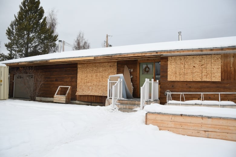 a wooden house with boarded-up windows