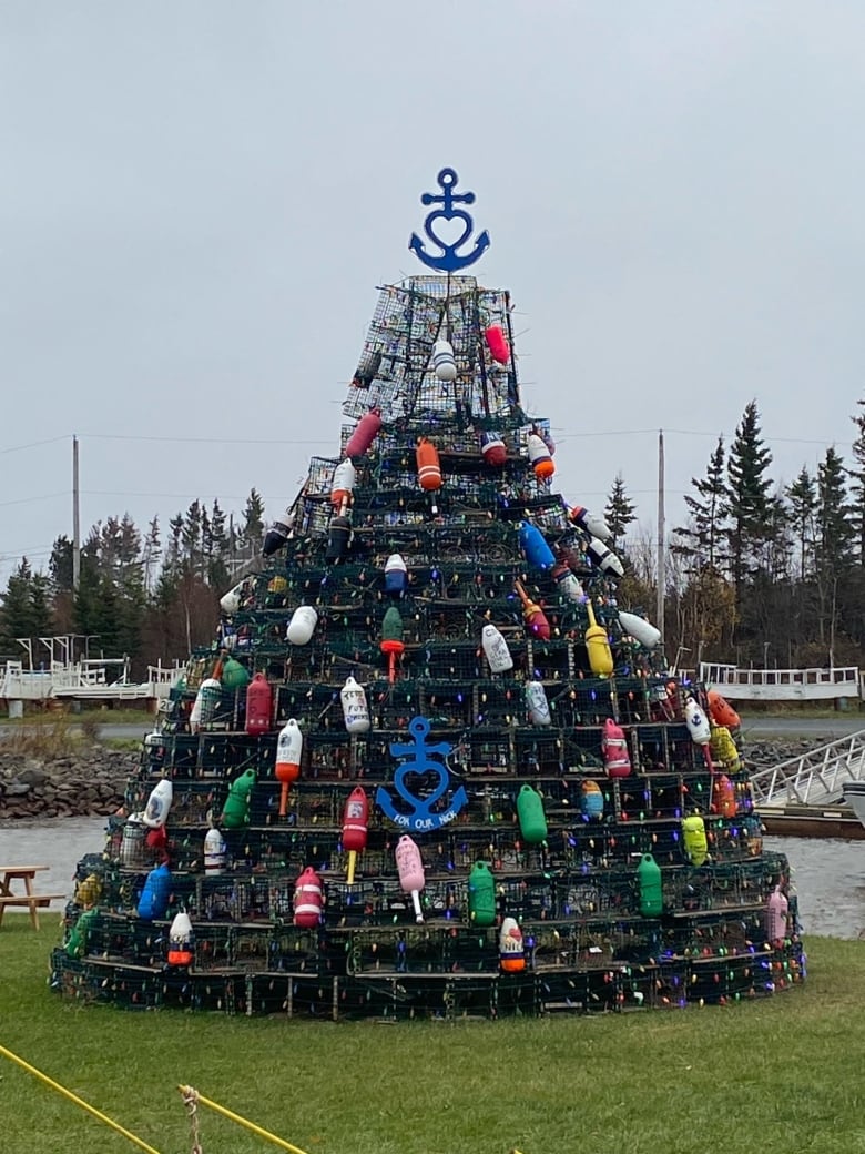 A group of lobster traps shaped into a pyramid covered in buoys topped with an anchor.