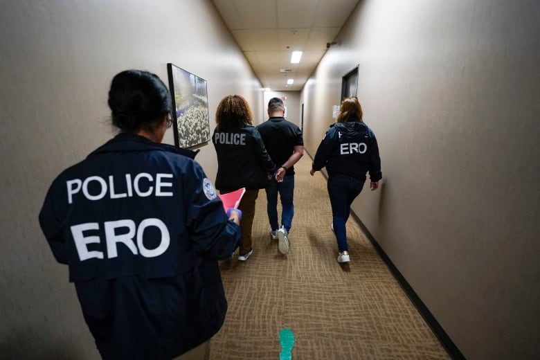 Immigration and Customs Enforcement officers escort a man detained at an immigration and customs processing facility, Wednesday, March 15, 2023, in San Diego. Some asylum-seekers who crossed the border from Mexico are waiting 10 years just for a court date. The Border Patrol released people with notices to appear at a U.S. Immigration and Customs Enforcement office. The move saved the Border Patrol untold hours processing court papers, but it left the job to an agency that had no extra staff for the increased workload. (AP Photo/Gregory Bull)