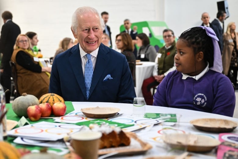 An adult and a child sit at a table with plates and food on it.