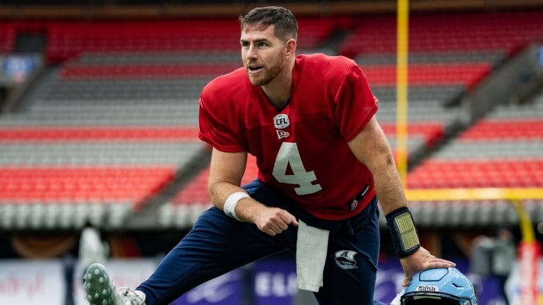 A men's football player stretches.