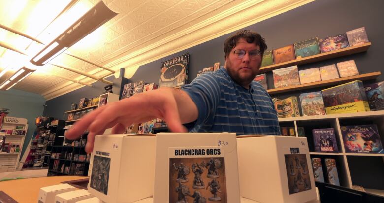 A man stacks little boxes in a store.