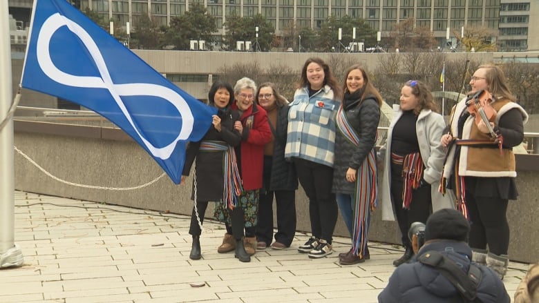 A Mtis Nation flag being raised at Toronto City Hall.