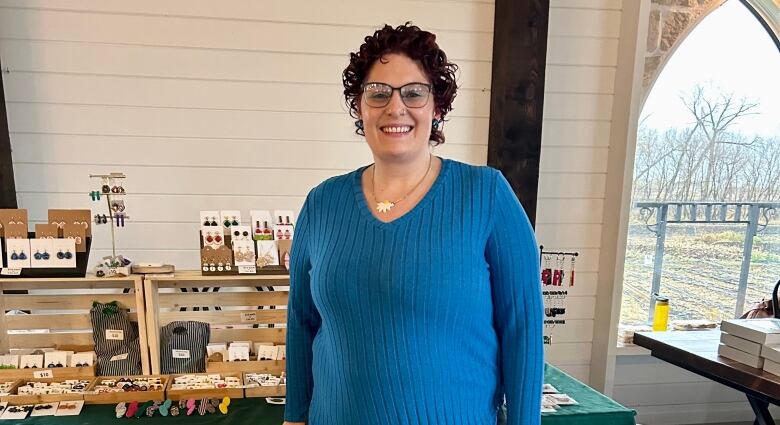 A woman standing in front of a stand with some jewelry mounted on it